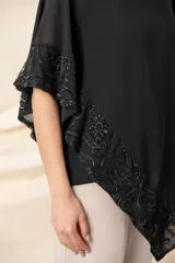 Blusa tipo poncho color gris con zócalo de tul bordado con motivos florales negros. Incluye una camiseta interior de spandex.