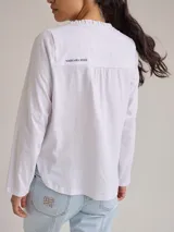 Remera color gris claro con cuello en V y volados de lino en el cuello.