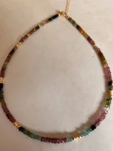 Collar corto de cuentas facetadas de turmalina multicolor con detalles de cuentas doradas.