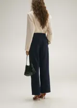 Pantalón de jean azul oscuro de corte wide leg, tiro medio, con pinzas delanteras y bolsillos laterales.