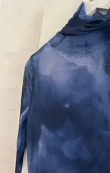 Vestido corto de microtul con estampado abstracto en tonos azules y celestes, cuello alto y mangas largas acampanadas.