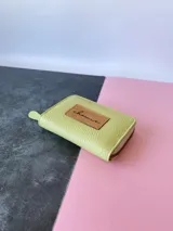 Billetera mini de cuero color verde lima, con cierre metálico y monedero interno.