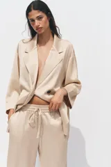 Pantalón de tiro alto color beige con cintura elástica ajustable con cordones, bolsillos delanteros y pernera ancha.