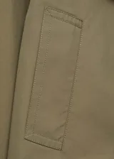 Chaqueta corta color verde oliva con cuello de pico con solapa, cierre cruzado con doble botonadura, solapas con muesca, dos bolsillos laterales y manga larga.