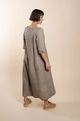 Vestido largo debajo de la rodilla, acampanado, color marrón, con cuello bote, bolsillos laterales y mangas 3/4 con detalle de tajo.