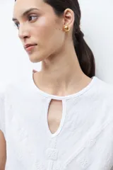 Remera verde petróleo con cuello redondo y abertura en forma de lágrima en el escote. Presenta un estampado geométrico en relieve y mangas cortas.