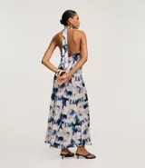 Vestido largo estilo slip con cuello halter que se ata en la nuca, sin mangas, con estampado abstracto en tonos azul y blanco que simula un efecto tie-dye.