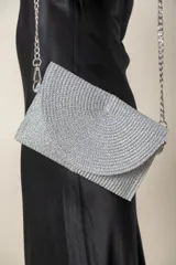 Sobre de fiesta plateado con textura tejida y cadena metálica para colgar.