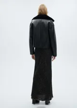 Chaqueta corta negra de cuero sintético con cuello y puños de piel sintética. Cierre frontal con botones y bolsillos de parche.