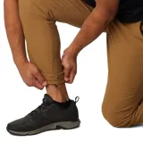 Pantalón de trekking color marrón claro, con protección solar UPF 50, repelente al agua y a las manchas. Cuenta con rodillas articuladas, puños cónicos, bolsillos con cremallera y detalles reflectantes.