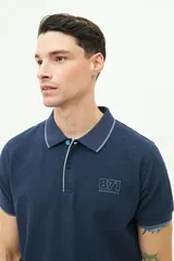 Polo color beige con textura, corte regular, logo estampado en el pecho y mangas cortas con ribete blanco.
