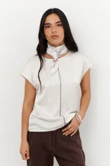 Blusa de manga 3/4 y cuello redondo, confeccionada en lino con acabado metalizado en tono beige o dorado claro.