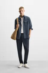 Pantalón negro de corte cropped, con cintura elástica ajustable con cordón, bolsillos laterales y traseros de vivo. El bajo tiene terminación con vuelta.