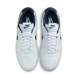 Championes urbanos Nike modelo Court Borough Low 2, color blanco con detalles en azul marino, confeccionados en cuero sintético, con logo "Nike" característico en los laterales y suela de goma.