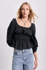 Blusa negra de punto smock con escote cuadrado, mangas largas abullonadas y corte peplum.