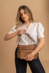 Bandolera de diseño moderno, color beige rosado, con correa regulable y bolsillo frontal con cierre.