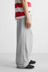 Pantalón jogger negro de corte ancho, confeccionado en tejido de algodón con interior de rizo. Cuenta con cintura elástica ajustable con cordón interior, bolsillos laterales y bolsillo trasero de parche.