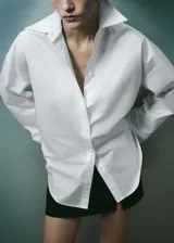 Camisa oversize blanca de popelina de algodón, con cuello camisero, manga larga con puños abotonados y cierre frontal con botones.