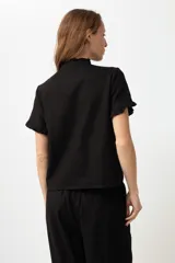 Camisa negra de lino con cuello mao y volados en cuello y mangas cortas.