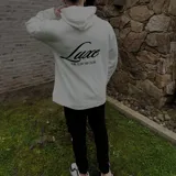 Buzo hoodie negro de corte oversize, con capucha, bolsillo frontal y estampa blanca en la espalda con la leyenda "Luxe" y "The Luxe Vip Club".