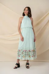 Vestido largo de gasa de seda color agua marina, con cuello halter, corte en la cintura elastizada y falda con volados y bordado de hilo de seda con relieve y canutillos en el ruedo.