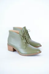 Botines de cuero color oliva con cordones frontales y tacón bloque de madera clara.