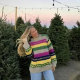 Sweater de lana merino color crema con cuello alto y diseño con motivos geométricos en amarillo, naranja, violeta y negro.