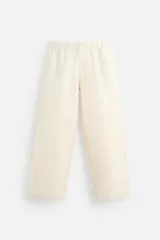 Pantalón color crema de corte amplio, con cintura elástica ajustable con cordón, bolsillos laterales y trasero, cierre frontal con cremallera y botón.