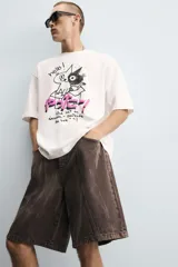 Camiseta blanca de corte holgado, con cuello redondo y mangas cortas. Estampado en el frente con dibujos de gatos, texto en japonés y frases en inglés.