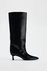 Bota de caña alta color negro de cuero sintético, con punta fina y tacón kitten.