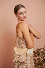 Vestido corto color ocre con bordado de motivos geométricos en color crema. Sin mangas, con cuello redondo y corte ajustado. Largo a la rodilla.