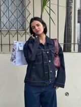 Campera de jean azul oscuro con costuras en hilo ocre, corte recto, cuello clásico, bolsillos frontales con solapa y cierre con botones metálicos.