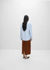 Camisa celeste de popelina de algodón y lyocell, de corte oversize, manga larga con puños abotonados, cuello camisero y cierre frontal con botones.