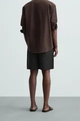 Bermuda negra de lino con calce relajado. Presenta cintura elástica ajustable con cordón, bolsillos frontales y un bolsillo trasero de plastrón.