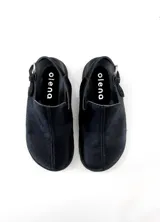 Zuecos negros de cuero con tira trasera y hebilla ajustable.