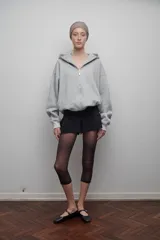 Campera gris confeccionada en felpa de algodón extra suave, con cierre metálico, bolsillos laterales y amplia capucha. Silueta oversize unisex.