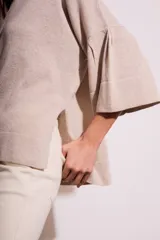 Sweater color salmón de tejido de punto con lurex, corte oversize, cuello redondo y mangas 3/4 acampanadas.