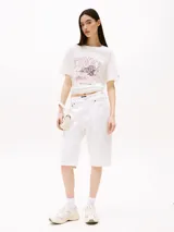 Remera blanca de algodón, corte amplio, con cuello redondo y mangas cortas. Estampado frontal con el logo "Tommy" y un paisaje tropical.