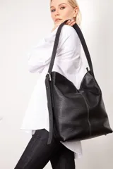 Bolso tipo tote de cuero gamuzado color marrón, con correa de hombro de cuero negro y hebilla metálica. Diseño minimalista y funcional. Confeccionado a mano en Uruguay.