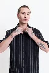 Camisa de manga corta con corte oversize, a rayas verticales blancas y grises, con cuello clásico y cierre frontal con botones. Confeccionada en algodón.