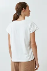 Remera color crudo con bordado de flores en el ruedo y mangas cortas.