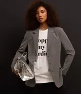 Blazer gris de poliéster, viscosa y elastano, de corte alargado, con cuello con solapas, bolsillos y cierre frontal con botones.