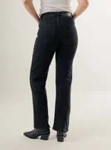 Pantalón de jean azul oscuro, de corte recto y tiro alto, con bolsillos delanteros y traseros. Presenta costuras verticales en el frente.