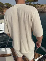 Buzo de punto color beige, de manga corta y cuello redondo.