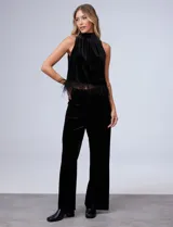 Conjunto de musculosa y pantalón en terciopelo negro, marca Julia Jordan. Blusa de cuello alto y terminación de ruedo con plumas. Pantalón con cintura elastizada.