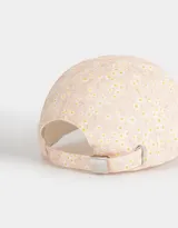 Gorra de béisbol color rosa con estampado de flores blancas y amarillas.
