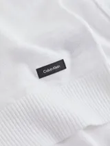 Sweater blanco de algodón orgánico con textura slub, cuello redondo, hombros caídos y etiqueta con logo de goma de Calvin Klein en el bajo.