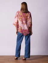 Blusa de gasa estampada con cuello a la base, escote en V y botón. Manga ¾ con terminación amplia y ruedo en pico.