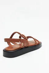 Sandalias color beige con plataforma negra, tiras trenzadas y ajuste con velcro en el talón.
