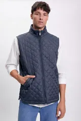 Chaleco azul marino con diseño capitoneado, cuello alto y cierre frontal con cremallera.